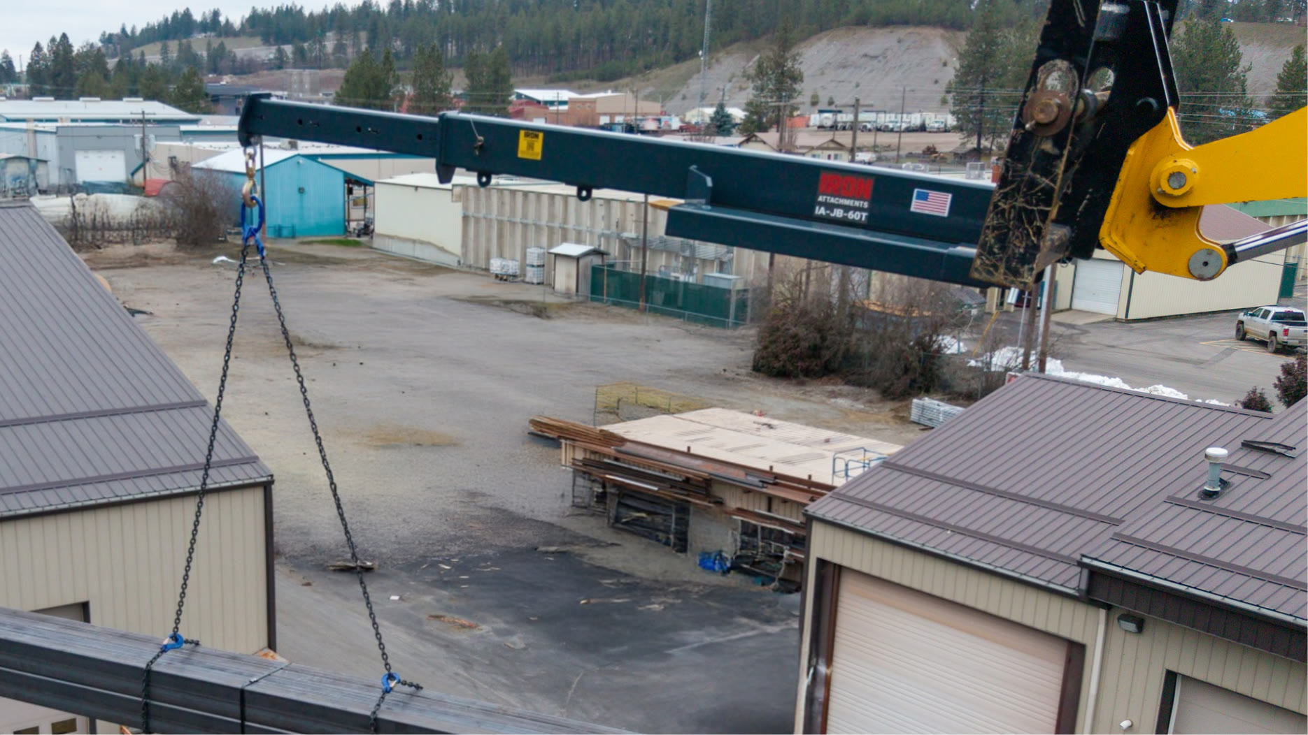 Iron Attach IA-JB-60T telescoping jib boom mounted on a telehandler lifting a steel load